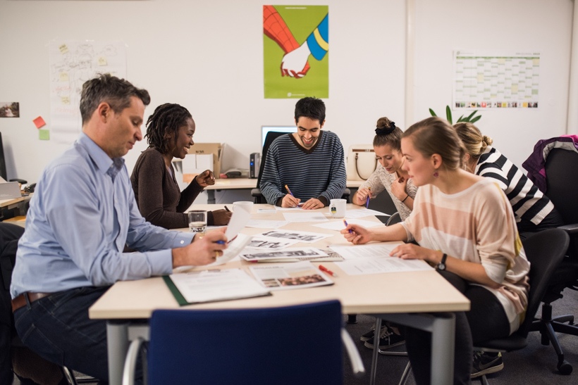 Beschäftigte und Studierende sitzen gemeinsam an einem Tisch und arbeiten an einem Kulturprojekt